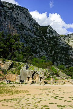 Ancient ruins of Delphi, Greece, with rocky mountains and blue sky.