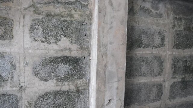 Camera pans across an unpainted grey concrete brick fence showing aged rustic texture