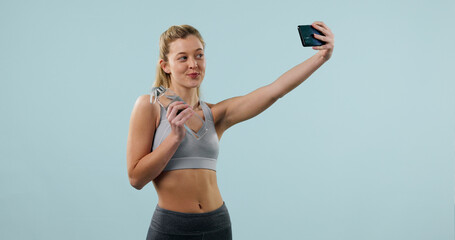 Obraz premium Woman, water bottle and selfie in studio for fitness, influencer and social media for gym space. Person, memory or post with content creation for exercise club, confidence and drink on background