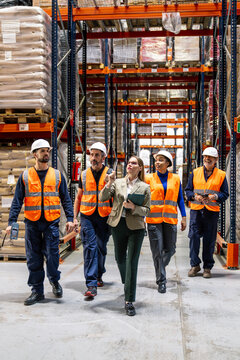 Diverse team of warehouse workers and managers discussing inventory and operations in a large distribution center