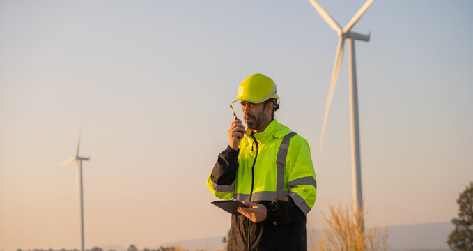 Engineer man working with tablet at windmill farm Generating electricity clean energy. Wind turbine farm generator by alternative green energy.