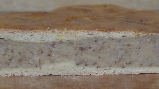 Close up of a freshly baked pie with potato and buckwheat filling, A slice of traditional Ukrainian Yavorivsky pie on a wooden board