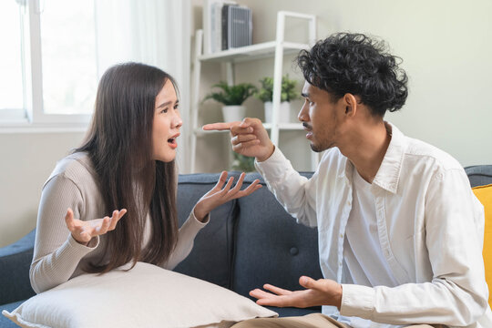 Family problem concept. Tension in relationship between married couple, husband and wife staying sitting separate after quarrel in the living room.