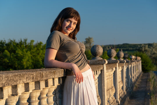 Young woman leaning on stone balustrade at sunset
