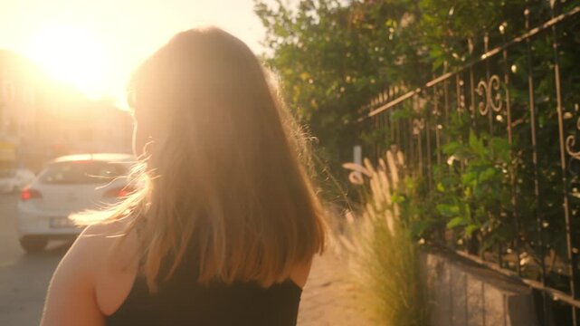 Sunset walk down a street with trees, a girl heads home with sun shining bright in the evening sky