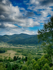 Obraz premium Sunny Carpathian peaks: green valleys and cloudy skies.