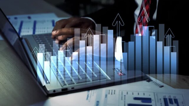 Businessman using a laptop with glowing holographic bar chart overlay on office desk, Business data growth finance analysis digital strategy and modern business planning at night