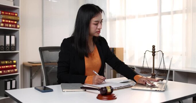 Professional asian lawyer working on litigation cases using a laptop in a modern law office representing justice, legal services, and online consultation for clients focusing on legal advice