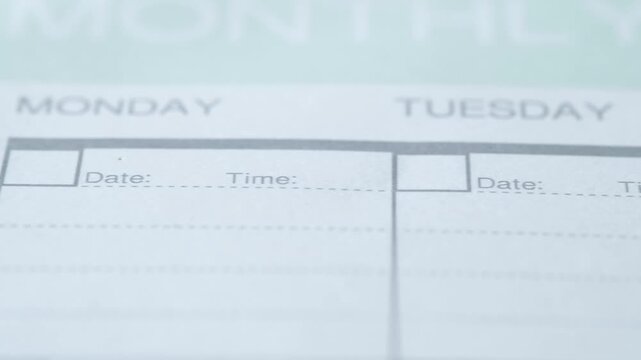 Close up camera panning across a monthly planner with blank spaces for date and time for monday, tuesday, and wednesday, with a pen coming into view on thursday