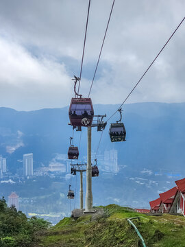 Genting Highlands, Malaysia - January 10, 2026: Cable car cabins descend the Genting Highlands mountain with the city valley and misty hills visible in the background below.