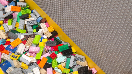 Obraz premium Pile of colorful Lego toy bricks and interlocking plastic building blocks mixed in a storage container next to a grey baseplate on June 15, 2026 in Bangkok, Thailand