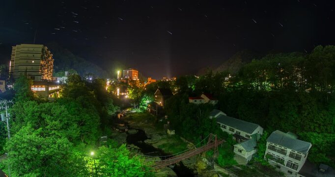 Jozankei Onsen Night Sky Timelapse: Star Trails and Futami Suspension Bridge over Toyohira River, Sapporo, Hokkaido, Japan - Wide Angle Shot
