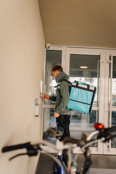 Delivery driver ringing apartment intercom for food delivery