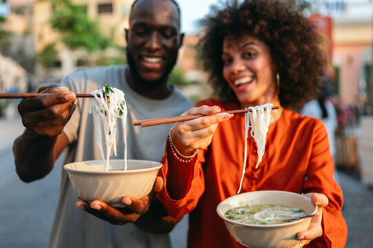 Diverse young friends enjoying street food together, sharing a happy, authentic multicultural moment