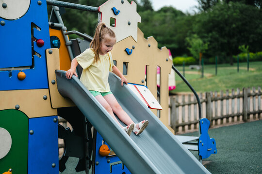 Little girl sliding at playground, summer holiday