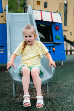 Little girl sliding at playground, summer time