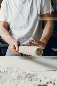A pizzaiolo rolls out dough for artisanal pizza. Isolated.
