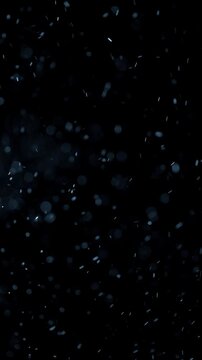 Blue Floating Particles on Dark Background. Soft glowing particles drift through darkness, creating an atmospheric abstract bokeh effect.