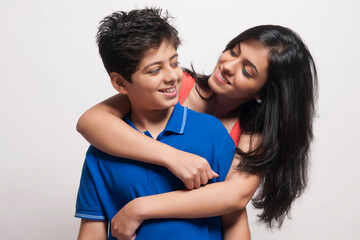 Fototapeta premium Portrait of Sister with arms around her brother looking at each other and smiling