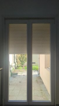 automatic roller shutter of a glass door windows sliding down and closing its blinds for privacy and security