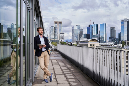 Businessman looking away while holding digital tablet on rooftop