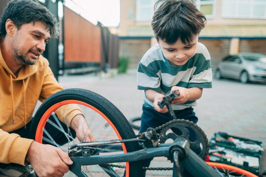 Father and son repair a bicycle together outdoors