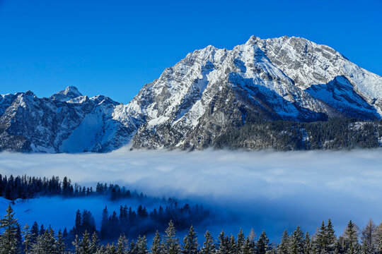 Snow capped Watzmann mountain above fog in Bavaria winter