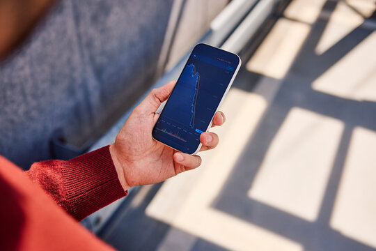 Hand holding smartphone showing financial crisis chart outdoors