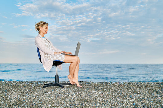 Businesswoman working on laptop on office chair at the beach