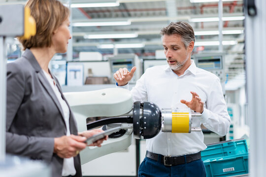 Businesswoman and man talking at assembly robot in a factory
