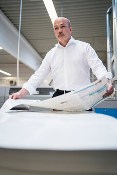 Businessman in a printing plant holding paper