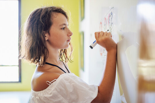 Portrait of smiling girl drawing on a whiteboard