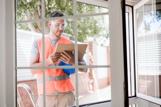 Maintenance engineer reading document on clipboard near window