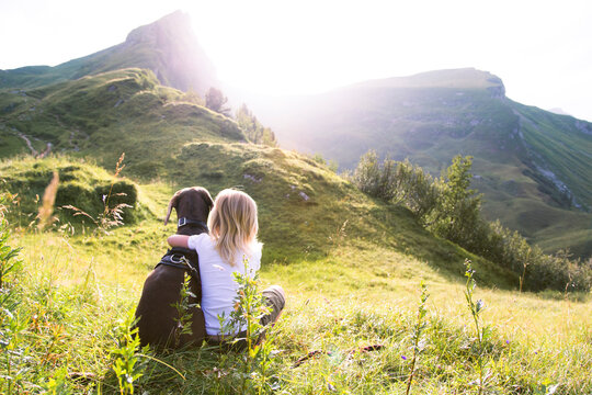 Austria, South Tyrol, young girl sitting with dog on meadow