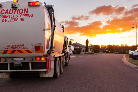 Garbage truck emptying bins at dusk on suburban street in Australian town