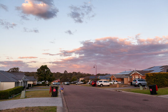 Sunset dusk sky above suburban street with emptied rubbish bins