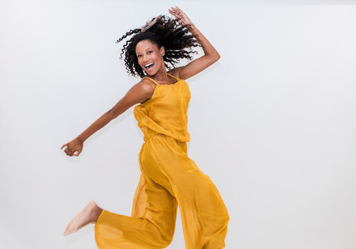 Carefree woman dancing while jumping on white background