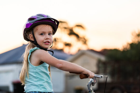 child in helmet looking over her shoulder in the evening while riding