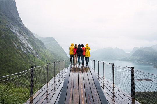Norway, Senja island, rear view of friends standing on an observation deck at the coast
