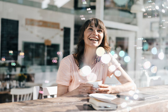 Woman sitting cafe, watching soap bubbles