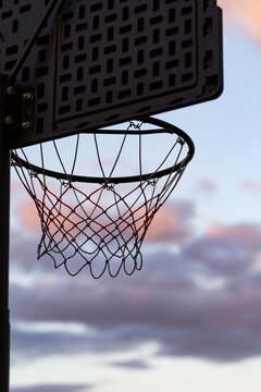 basketball net silhouetted against pastel dusk clouds in sky