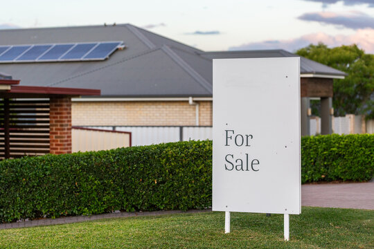 for sale sign outside home with neat green hedges