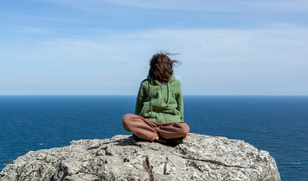 Traveler sitting on a rock by the sea with face covered