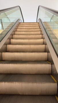 Escalator steps rising, modern transport facility interior. Low angle, vertical shot.
