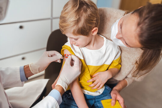Boy getting bandage by doctor after vaccination at center