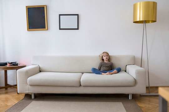 Bored girl sitting on the couch at home
