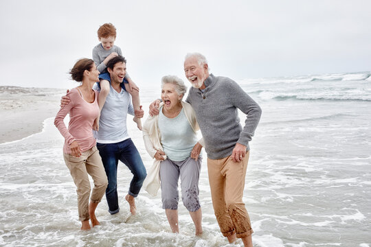 Happy couple spending quality time at the beach with son and grandparents