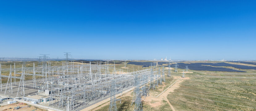 Aerial View of a Large High-Voltage Substation in Arid Grassland with Adjacent Solar Farms and Distant Power Plants