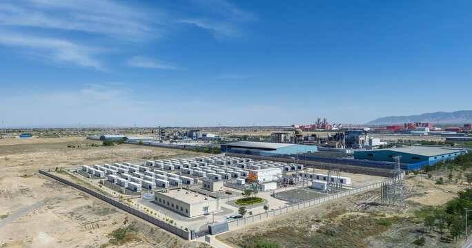 Aerial View of a Grid-Connected Battery Energy Storage Power Station Adjacent to Industrial Complex in Arid Region