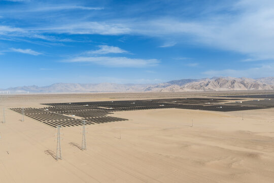 Aerial View of Massive Solar Photovoltaic Farm in Gobi Desert with Kunlun Mountains and Transmission Infrastructure